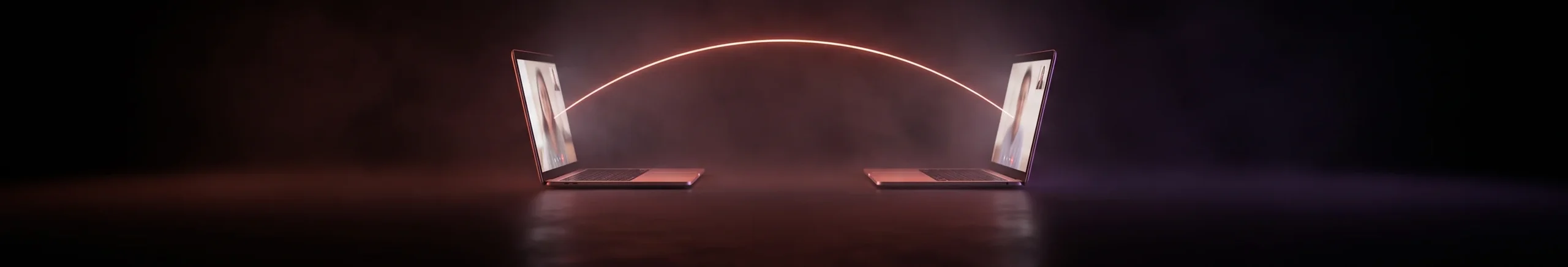 Two laptops facing each other in the dark, joined by an arc of light, suggesting a live one-to-one video conversation