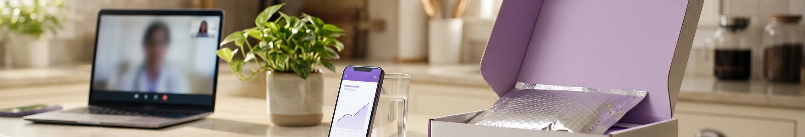 Kitchen counter in morning light with a laptop video call, a phone showing a weight care app and an open delivery box with a cold pack